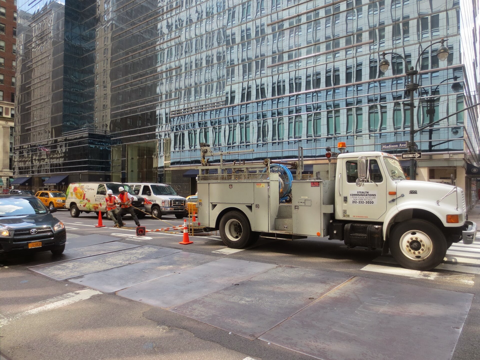 Workers in a street trench laying fiber-optic cable and conduit for a broadband installation.