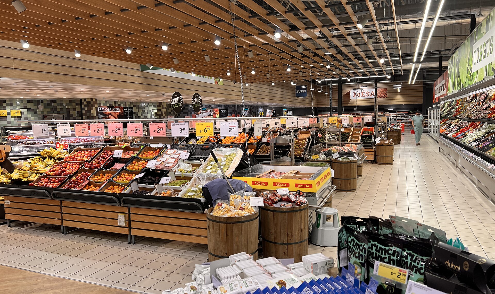 Bins of fresh fruit and vegetables line the produce section of a brightly lit supermarket.